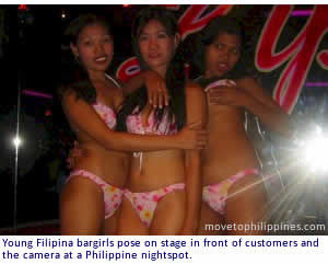 Young Filipina bargirls pose on stage in front of customers and the camera at a Philippine nightspot