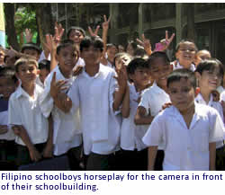 Filipino schoolboys horseplay for the camera in front of their schoolbuilding