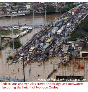 Pedestrians and vehicles crowd this bridge as floodwaters rise during the height of typhoon Ondoy (Ketsana)