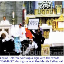 Carlos Celdran holds up a sign with the words "DAMASO" during mass at the Manila Cathedral