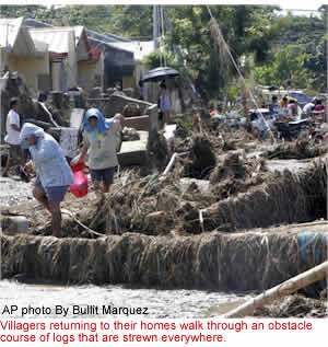 Villagers returning to their homes walk through an obstacle course of logs that are strewn everywhere