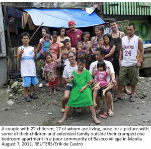 A couple with 22 children, 17 of whom are living, pose for a picture with some of their children and extended family outside their cramped one bedroom apartment in a poor community of Baseco village in Manila August 7, 2011. REUTERS/Erik de Castro