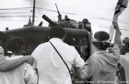 EDSA demonstrators lock arms in front of a military vehicle hoping to prevent it from moving forward