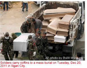 Soldiers carry coffins to a mass burial on Tuyesday, Dec 20, 2011 in Iligan City